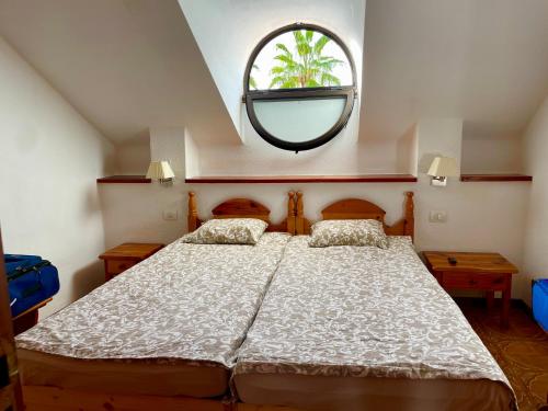 1 dormitorio con 1 cama grande y una ventana redonda en Sunny 2-bedroom apartment in Parque Santiago II en Playa de las Americas