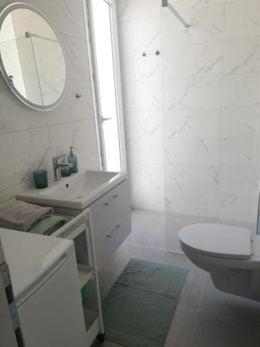 a white bathroom with a sink and a mirror at Villa apartment Laganini in Okrug Gornji