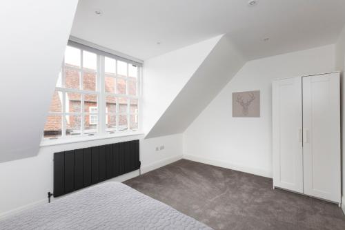an attic bedroom with white walls and a window at Hampden Apartments - The William in Eton