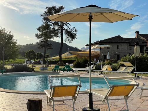 a pool with two chairs and an umbrella at Ca' Virginia Country House Wellness in Montecalvo in Foglia