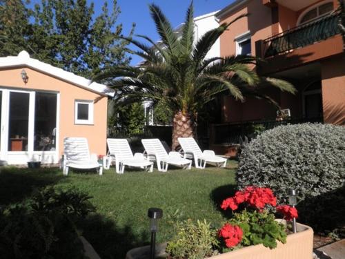 un patio con sillas blancas y una palmera en Villa Dolce Vita, en Vodice