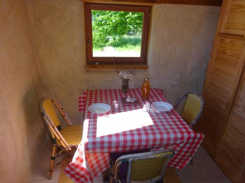 a table with a red and white checkered table cloth at maisonnette écologique isolée en botte de paille in Ploërmel