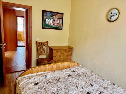 ein Schlafzimmer mit einem Bett und einer Uhr an der Wand in der Unterkunft Gedimino Apartamentai in Juodkrantė