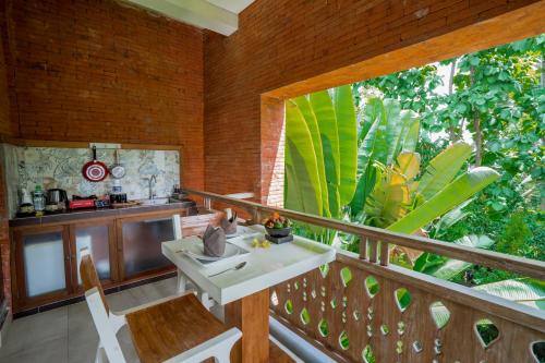 Habitación con balcón con mesa y sillas. en KajaNe Yangloni at Ubud Bali en Ubud
