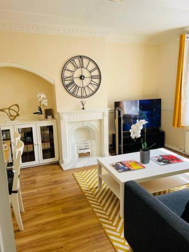 a living room with a table and a clock on the wall at Superb and Comfortable 3BD Home in Dagenham in Dagenham