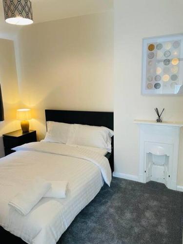 a bedroom with a white bed and a fireplace at Superb and Comfortable 3BD Home in Dagenham in Dagenham