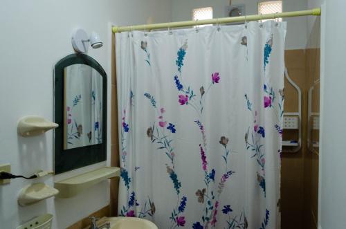 uma casa de banho com uma cortina de chuveiro com flores em La Posada de Joselito em Crucita