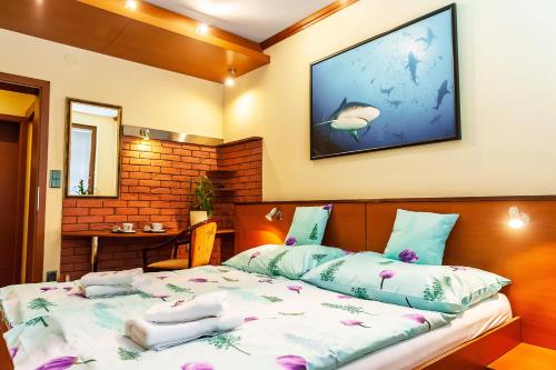 1 dormitorio con 1 cama con almohadas y TV en la pared en Hotel Áčko en Ružomberok