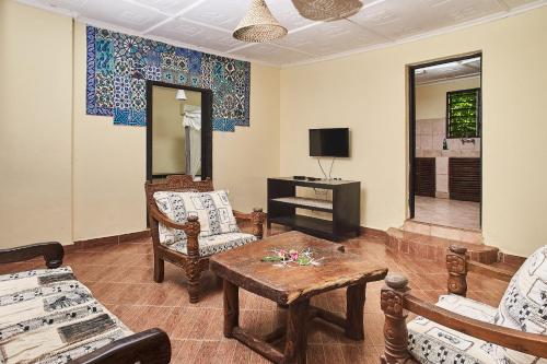 een woonkamer met stoelen en een tafel en een televisie bij Coral Beach Resort in Diani Beach