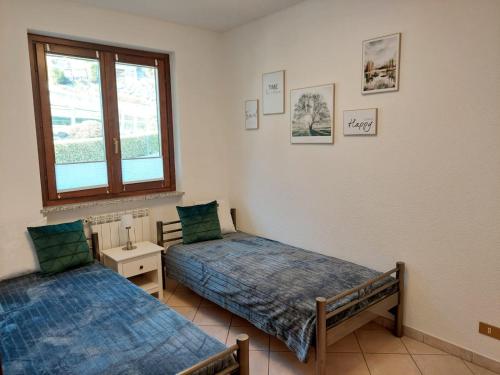 sypialnia z 2 łóżkami i oknem w obiekcie Residenza La Rocca w mieście Castello Valsolda