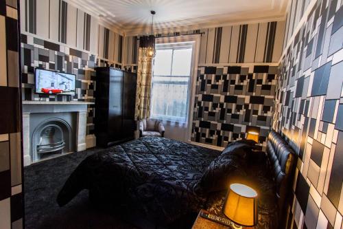a bedroom with a large bed and a television at The Carlton Hotel in Folkestone