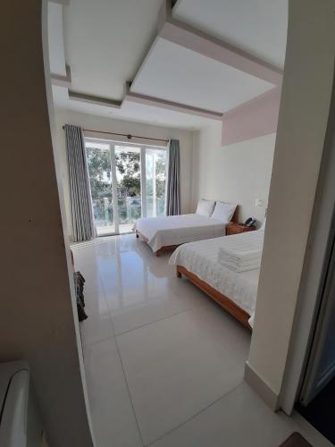 a white bedroom with two beds and a window at Sài Gòn Phan Rang Hotel in Thôn Mỹ Phước