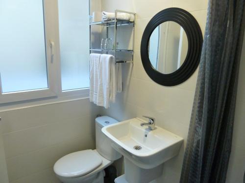 a bathroom with a toilet and a sink and a mirror at Hostal Lauria in Madrid