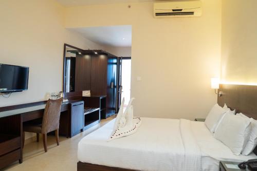 a hotel room with a bed and a desk and a television at Greenleaf The Resort & Spa, Ganpatipule in Ganpatipule