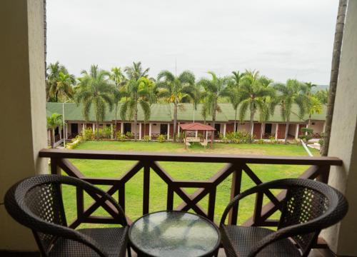 a balcony with chairs and a view of a resort at Greenleaf The Resort & Spa, Ganpatipule in Ganpatipule
