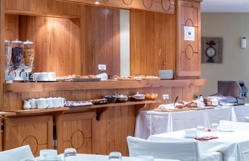 a restaurant with white tables and food on display at Hôtel Causse Comtal Rodez, The Originals Relais in Gages-le-Haut
