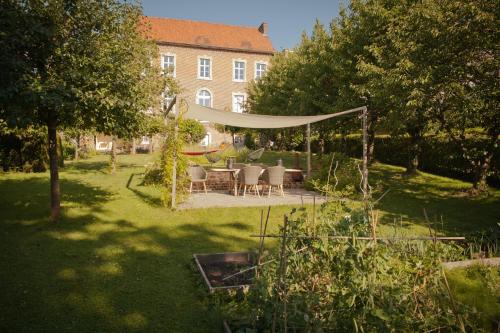 - un jardin avec une table, des chaises et un hamac dans l'établissement B&B De Kersentuin, à Looz