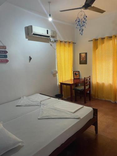 a bedroom with a bed and a table and yellow curtains at Hope Hostels, Varkala - Helipad in Varkala
