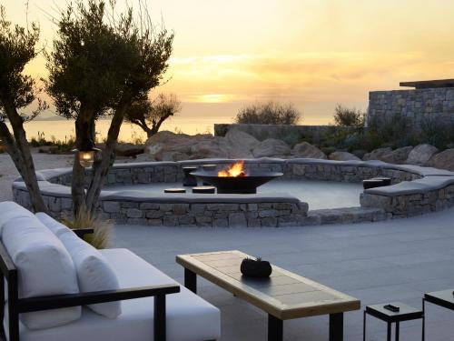 a patio with a fire pit and a table and benches at Kalesma Mykonos in Ornos