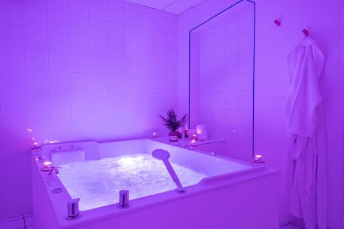 - une salle de bains pourpre avec une baignoire et un miroir dans l'établissement Hôtel Causse Comtal Rodez, The Originals Relais, à Gages-le-Haut