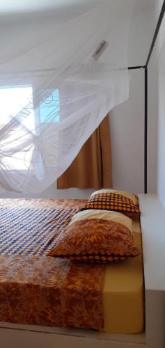 a bed with a net on top of it at DEKK JAMM, où l'on trouve la paix in Toubab Dialaw