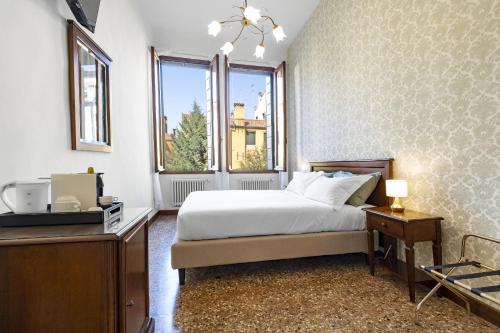 a bedroom with a bed and a desk and a window at Residenza Centopietre - Dorsoduro in Venice