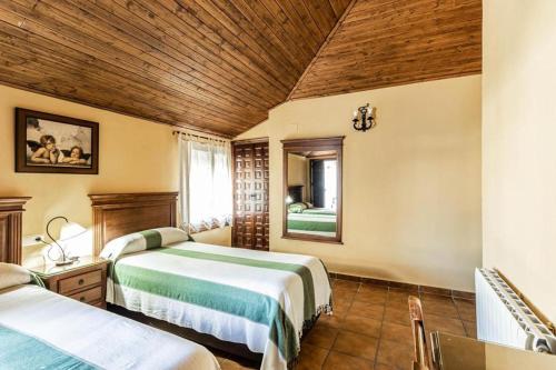 a bedroom with two beds and a wooden ceiling at Complejo turistico El Álamo in Hornachuelos