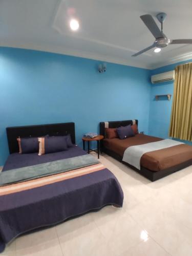 a bedroom with two beds and a blue wall at Homestay Banglo Alor Setar in Alor Setar