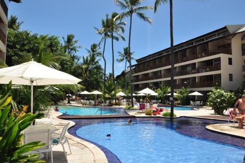 a pool at a resort with palm trees and umbrellas at Nannai Residence Apartament in Porto De Galinhas