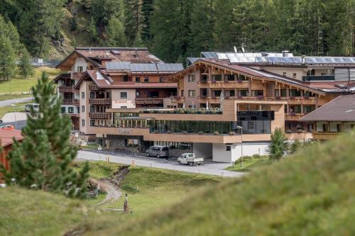a large building with cars parked in front of a road at 4 Sterne Superior Mühle Resort 1900 - Adults only in Obergurgl