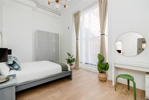 Majestic Luxury Apartment in Marylebone في لندن: غرفة نوم بيضاء مع سرير ومرآة