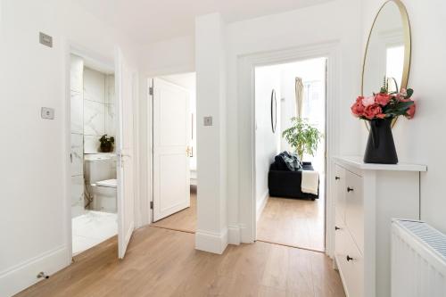 a white bathroom with a mirror and a vase of flowers at Majestic Luxury Apartment in Marylebone in London