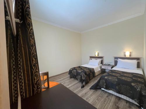 a hotel room with two beds and a table at Hotel Euphrat Nemrut in Karadut