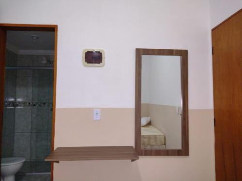 La salle de bains est pourvue d'un miroir, d'un lavabo et de toilettes. dans l'établissement Pousada Bela Rainha, à Aparecida