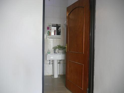 a bathroom with a sink and a wooden door at Villa Kikiriki in Kigali