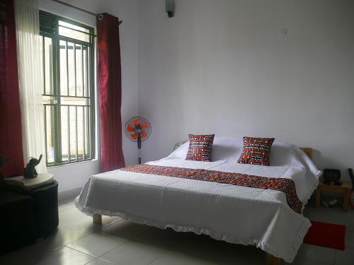 a bedroom with a white bed with pillows and a window at Villa Kikiriki in Kigali