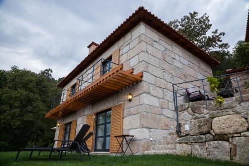een stenen huis met een balkon ernaast bij Quinta da Bouça - Agroturismo in Paços de Gaiolo