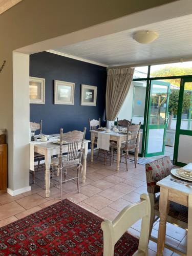 ein Esszimmer mit Tischen und Stühlen und einer blauen Wand in der Unterkunft Sandra's Guest House in Langebaan