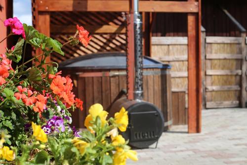 a wood stove sitting outside of a building with flowers at Viesu māja Ramatas in Skulte