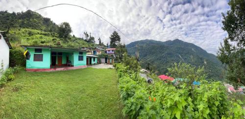 une maison dans un champ avec des montagnes en arrière-plan dans l'établissement Solitude Homestay, Agoda, à Uttarkāshi