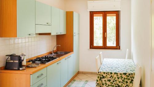 a kitchen with white cabinets and a table and a window at Villa Verde in Procchio