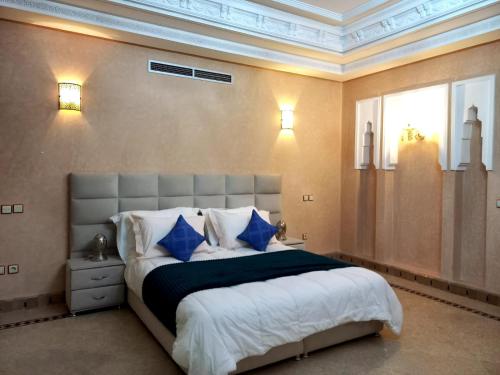 1 dormitorio con 1 cama grande con almohadas azules en CYCAS VILLA TARGA GARDEN -Only Family, en Marrakech