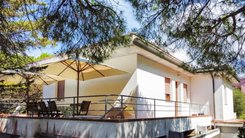 a house with a balcony with chairs and an umbrella at Villa Verde in Procchio