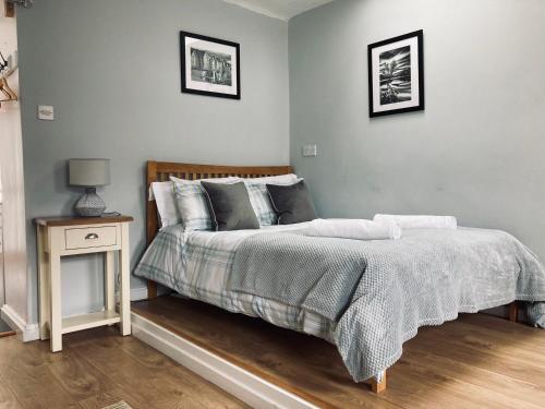 a bedroom with a bed and a night stand with a lamp at Stiwdio Eithinog in Caernarfon
