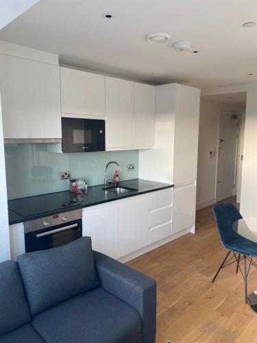 a kitchen with white cabinets and a blue couch at Morden 1 bedroom City- Apt Central stylish living in Croydon