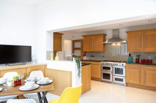 a kitchen with wooden cabinets and a table with chairs at Central Ashford Stay - Contractors & Families Welcome - Free Parking in Kent