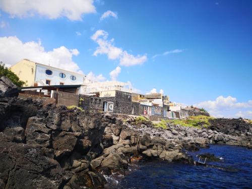 a group of houses on a rocky hill next to the water at B&B Acireale - Il Cavalluccio Marino Fronte Mare in Acireale