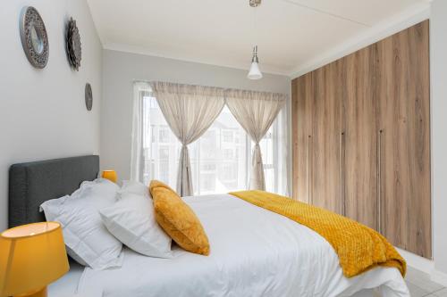 een slaapkamer met een wit bed en een gele deken bij The Blyde Luxurious Villa in Pretoria