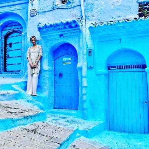 a woman standing in front of a blue building at Casa Plasa Grande chefchaouen in Chefchaouene
