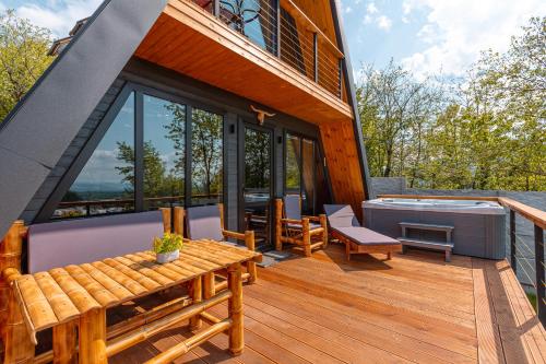 a house with a deck with a hot tub and a table at Modern Wood Cottages in Mtskheta